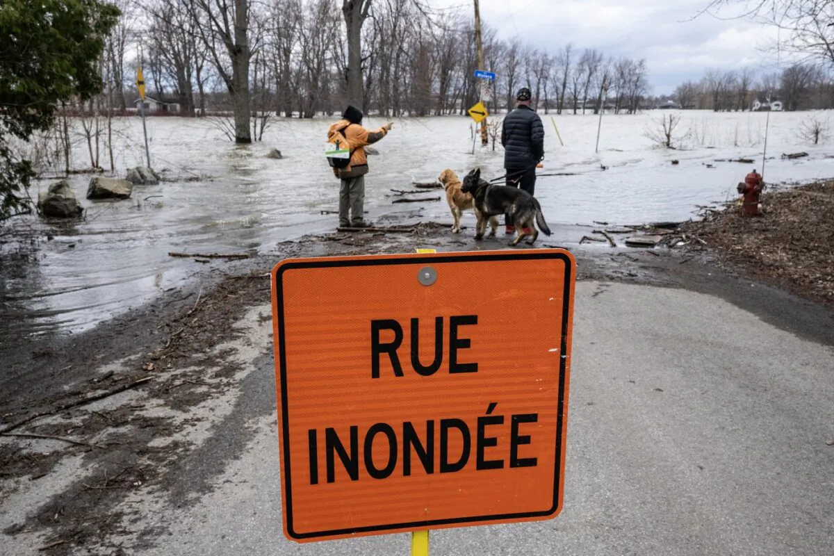 People look at the rising waters of the Milles-Iles river in Laval, Que., on April 18, 2023. (The Canadian Press/Ryan Remiorz)