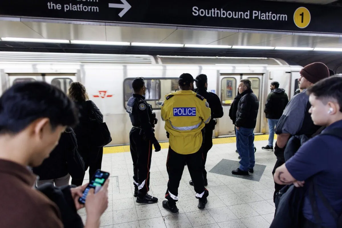 Police officers are seen on the platform as people wait for a subway train inside a TTC station in downtown Toronto, April 1, 2023. (The Canadian Press/Cole Burston)