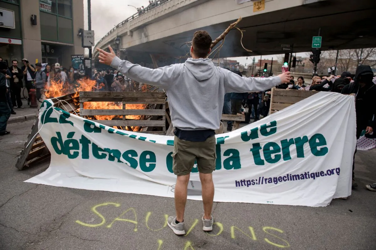 A man stands in front of a barricade on fire put up by Black Bloc at the end of the Earth Day Protest, in Montreal, Canada, on April 22, 2023. (Andrej Ivanov/AFP via Getty Images)