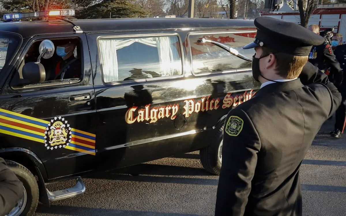 Firefighters salute as the hearse and honour guard pass by at the regimental funeral service for Sgt. Andrew Harnett in Calgary on Jan. 9, 2021. (The Canadian Press/Jeff McIntosh)