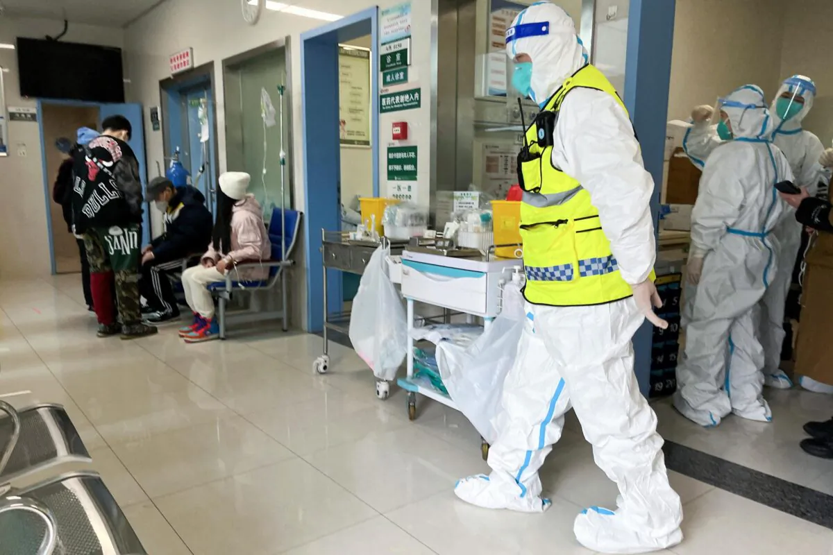 A security personnel in a protective suit keeps watch as medical workers attend to patients at the fever department of Tongji Hospital, a major facility for patients of COVID-19 in Wuhan, Hubei Province, China, on Jan. 1, 2023. (Reuters)