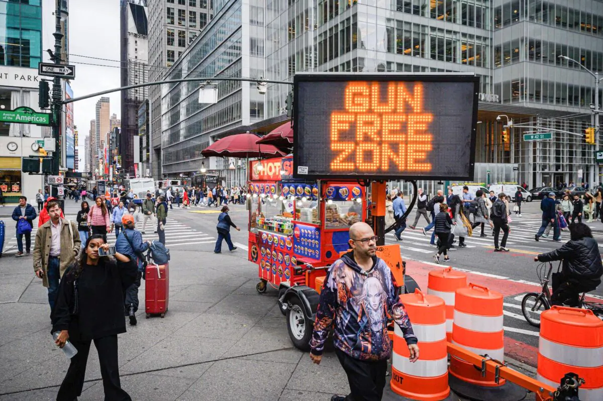 Pedestrians pass an anti-gun sign in New York city on October 13, 2022. (Ed Jones/AFP via Getty Images)