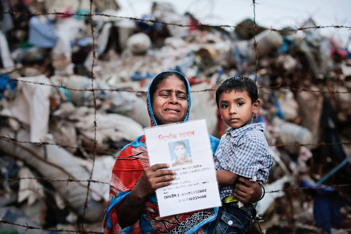 FILE - In this Friday, June 14, 2013 file photo, Bangladeshi Maksuda holds a picture of her son Mehedi who was a garment worker and is missing following the collapse of the Rana Plaza building as she poses next to the rubble in Savar, near Dhaka, Bangladesh. A delegation of the U.S. Trade Representative’s office is on a five-day visit to Bangladesh ending Wednesday, Sept. 23, 2015, to see the improvement of safety standards at factory sites and changes to legal documents allowing for wider workers’ rights, key conditions for regaining the Generalized System of Preferences facility under which the United States allows imports of more than 5,000 goods from 122 of the world’s poorest countries with low or zero-tariff benefits. The trade benefit was withdrawn after the collapse of Rana Plaza, a building complex housing five garment factories outside the capital, Dhaka in 2013. The garment industry is crucial to Bangladesh’s economy as it employs about 4 million workers, mostly rural women, and many other sectors including banks are heavily dependent on it. (AP Photo/Kevin Frayer, File)