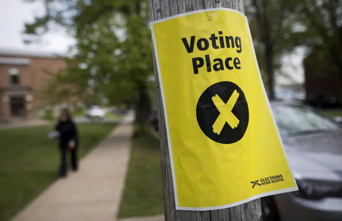 A sign marking a polling station is seen as a pedestrian walks past in Halifax on Nova Scotia's provincial election day on May 30, 2017. (The Canadian Press/Darren Calabrese)