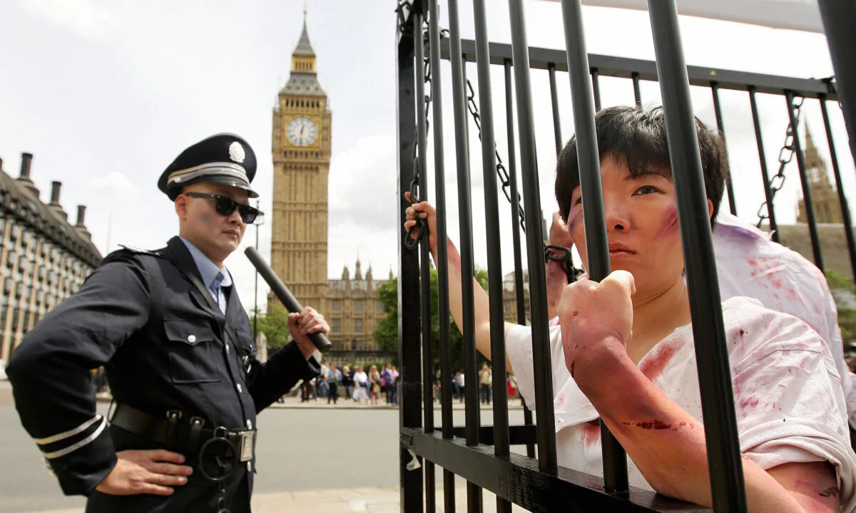 Torture reenactment: ﻿A Falun Gong adherent dressed as a ﻿Chinese policeman stands ﻿guard over a cage containing Falun Gong practitioners, during a demonstration outside London's Houses of Parliament, on July 20, 2009. (Shaun Curry/AFP via Getty Images)