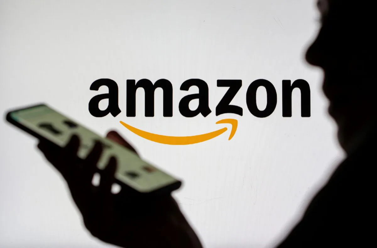 Woman with smartphone in front of displayed Amazon logo on July 30, 2021. (Dado Ruvic/Illustration/Reuters)