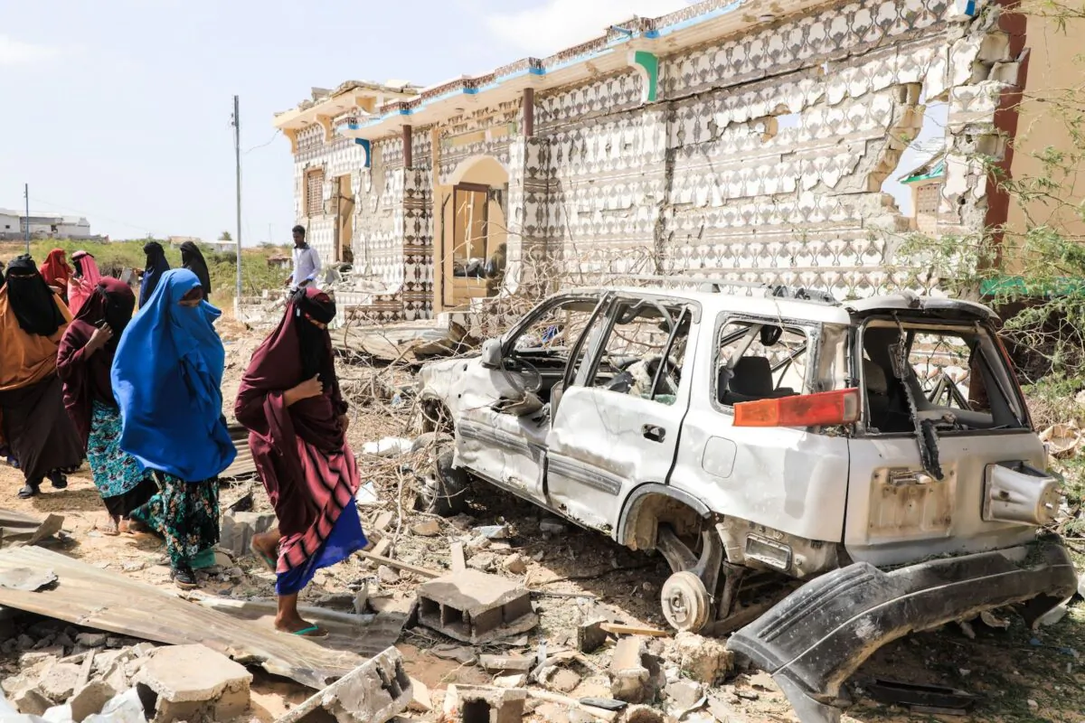 Women walk next to a destroyed house after an explosion by al-Shabaab terrorists during an attack on a police station on the outskirts of Mogadishu, Somalia, on Feb. 16, 2022. (Hassan Ali Elmi/AFP via Getty Images)