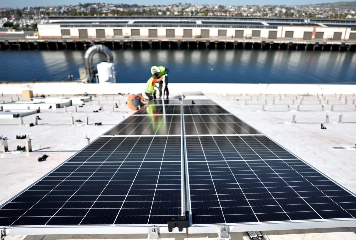 Workers install solar panels during the completion phase of a 4-acre solar rooftop atop AltaSea's research and development facility at the Port of Los Angeles on April 21, 2023. (Mario Tama/Getty Images)