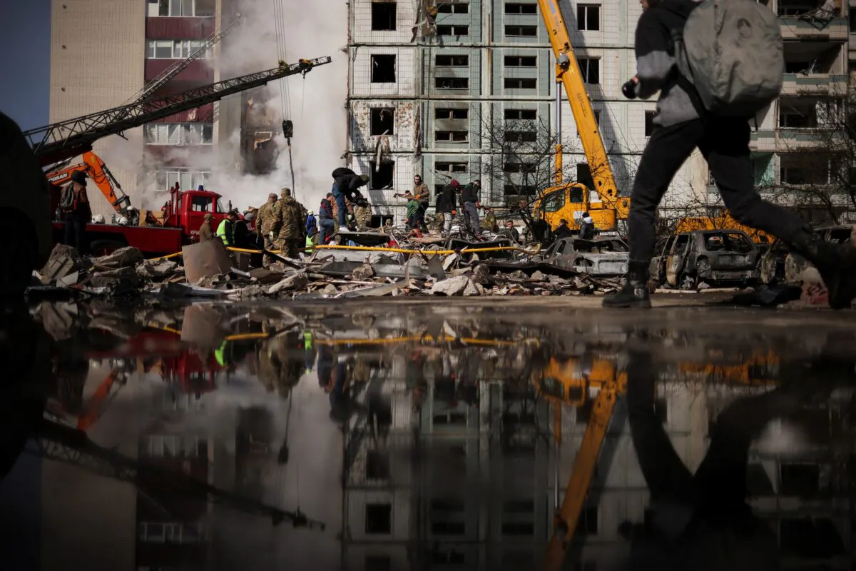 Local residents and rescuers stand amidst the rubble at the site of a heavily damaged residential building hit by a Russian missile in the town of Uman, Cherkasy region, Ukraine, on April 28, 2023. (Carlos Barria/Reuters)