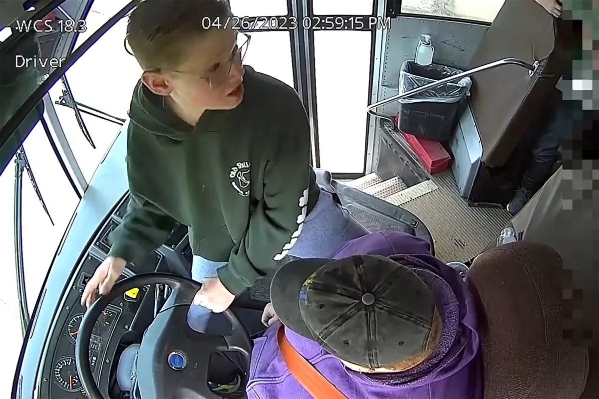 Seventh-grader Dillon Reeves grabs the steering wheel on his school bus and hits the brakes after the driver passed out in Warren, Mich., on April 26, 2023, in a still from video. (Warren Consolidated Schools via AP)