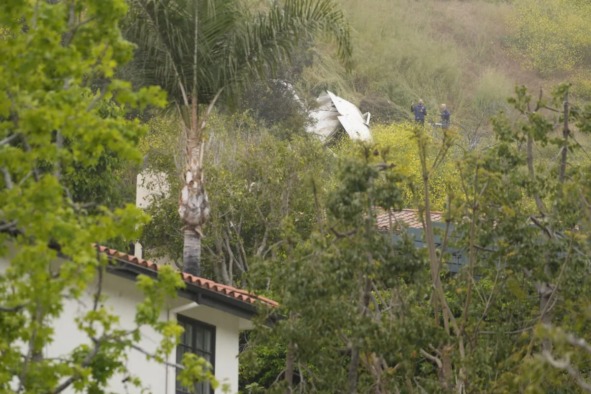 National Transportation Safety Board investigators inspect a downed plane on a steep hill above a home on Beverly Glen Circle in Los Angeles on April 30, 2023. (Damian Dovarganes/AP Photo)