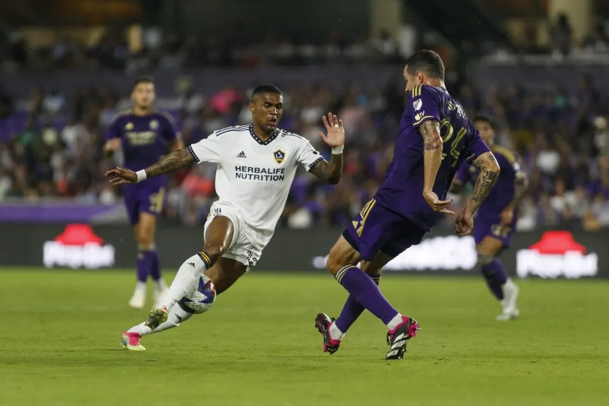 Orlando City SC defender Kyle Smith (24) passes the ball through the legs of Los Angeles Galaxy midfielder Douglas Costa (10) in the first half at Exploria Stadium in Orlando, Fla., on April 29, 2023.(Morgan Tencza/USA TODAY Sports via Field Level Media)