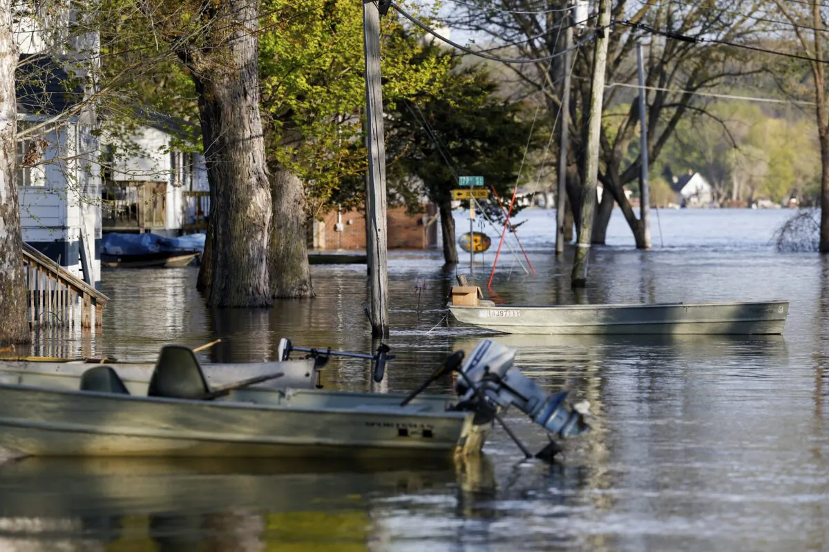Boats float tethered in the front yards of homes along South Spencer Road as the Mississippi River continues to rise forcing residents to make alternative transportation between their homes and the rising water covering their street in Pleasant Valley, Iowa, on April 27, 2023. (Nikos Frazier/Quad City Times via AP)
