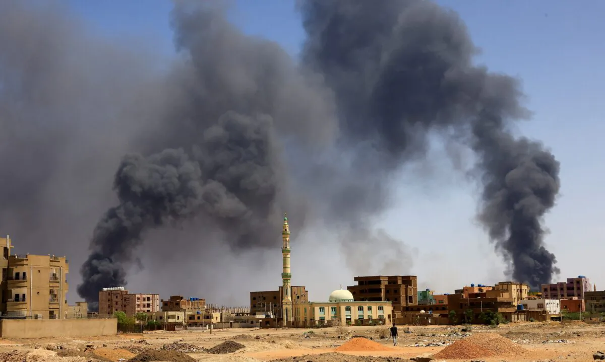 A man walks while smoke rises above buildings after aerial bombardment, during clashes between the paramilitary Rapid Support Forces and the army in Khartoum, Sudan, on May 1, 2023. (Mohamed Nureldin Abdallah/Reuters)
