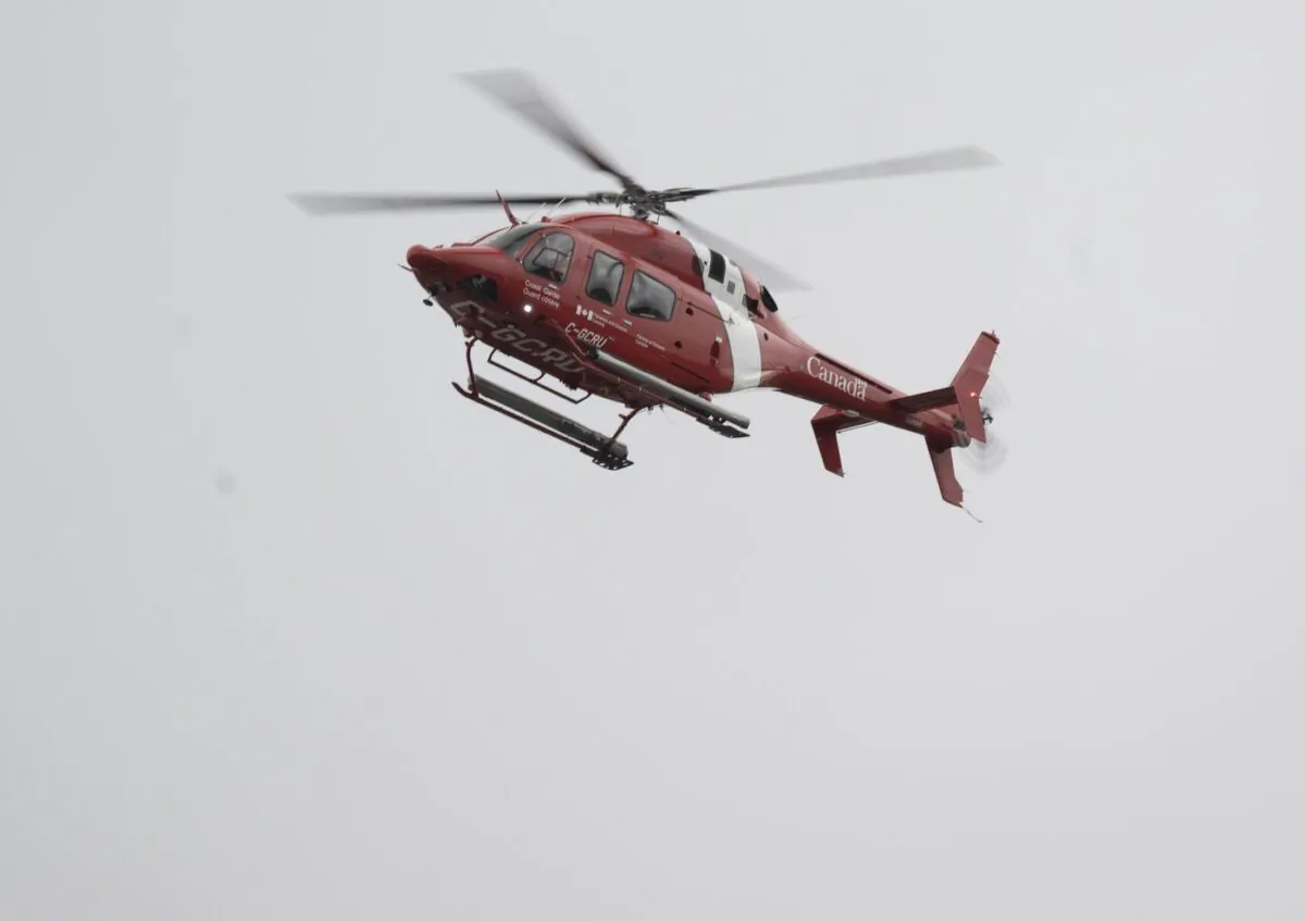 A Canadian Coast Guard helicopter patrols the river looking for two missing firefighters after major spring floods hit the Charlevoix region, May 2, 2023, in Baie-St-Paul, Que. (The Canadian Press/Jacques Boissinot)
