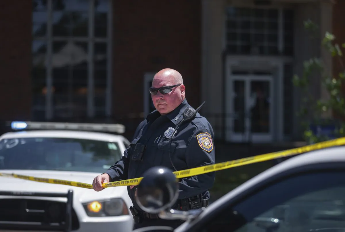 A Memphis Police officer extends crime scene tape around the perimeter of an active shooter situation near the University of Memphis in Tenn. on May 2, 2023. (Patrick Lantrip/Daily Memphian via AP)