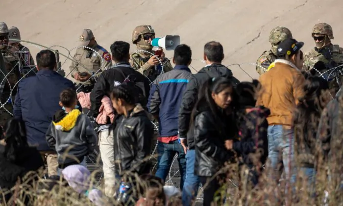 A Texas National Guard soldier speaks to immigrants at high-traffic illegal border crossing area along Rio Grande in El Paso, Texas, on Dec. 20, 2022. (John Moore/Getty Images)