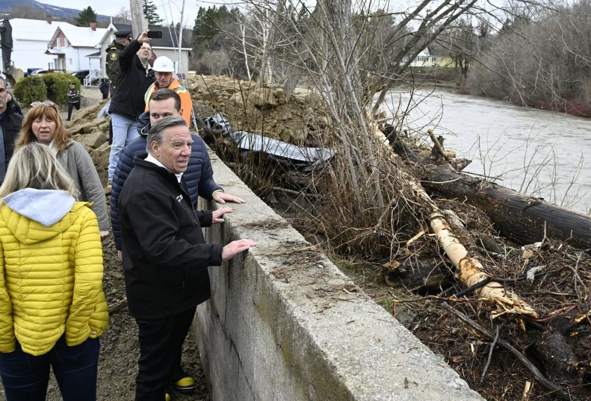 Quebec Premier François Legault watches the Rivière du Gouffre flow as he tours the site of a major spring flood, May 3, 2023, in Baie-St-Paul, Que. (The Canadian Press/Jacques Boissinot)