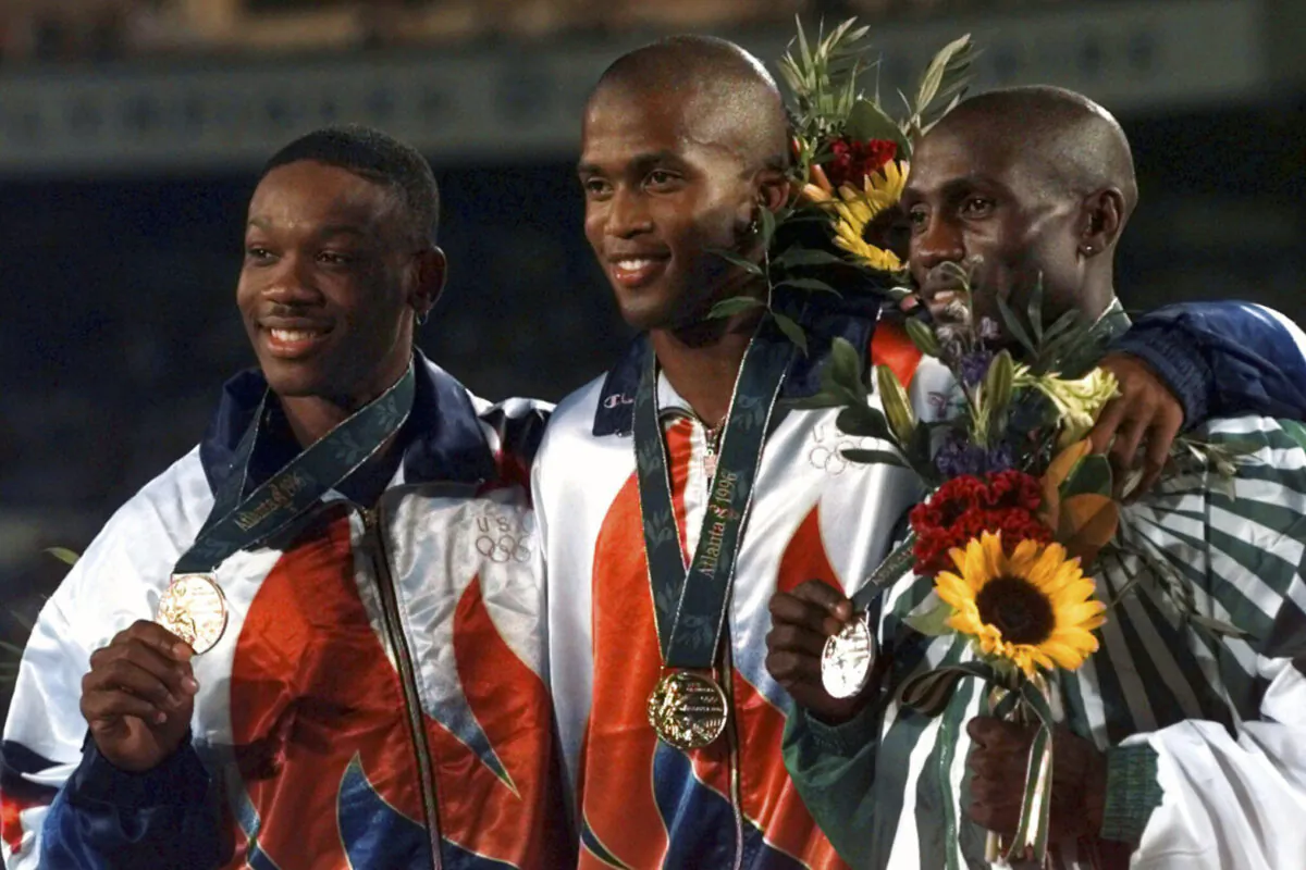 United States gold medalist Derrick Adkins is flanked by teammate and bronze medalist Calvin Davis (L) and silver medalist Samuel Matete of Zambia (R) after the 400 meter hurdle final at the 1996 Summer Olympic Games in Atlanta on Aug. 1, 1996. (Ed Reinke/AP Photo)