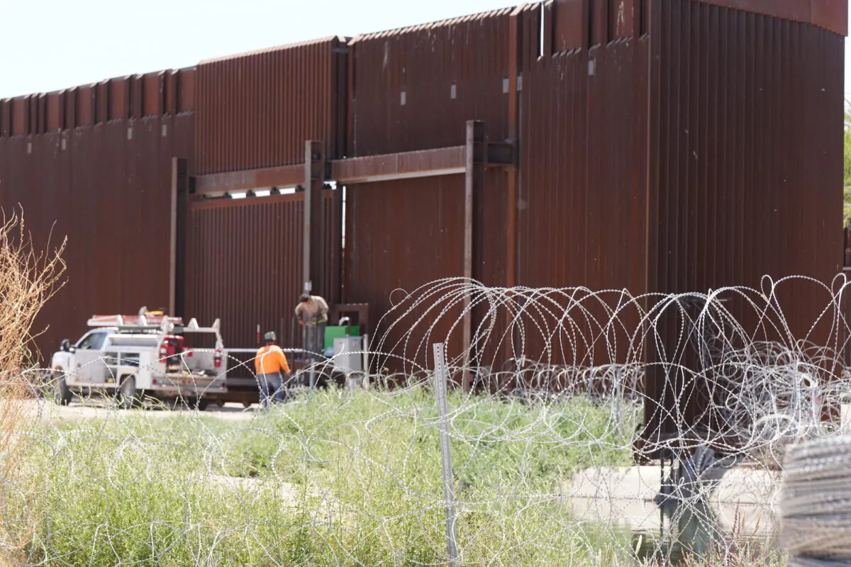 Independent contractors work near a section of border fence in San Luis, Ariz., on May 4, 2023. (Allan Stein/The Epoch Times)