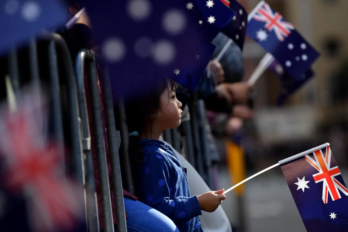 Members of the public wave the Australian flag as they watch the Anzac Day March in Sydney, Australia, on April 25, 2023. (AAP Image/Bianca De Marchi)