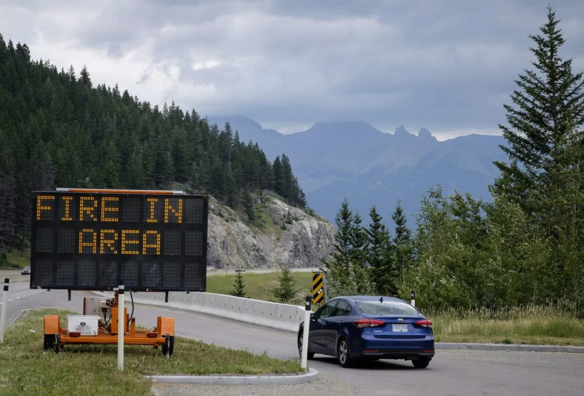 A sign warns of a forest fire in the area as smoke haze from forest fires burning in Alberta and British Columbia hangs over Banff, Alta., in Banff National Park, on July 21, 2017. (The Canadian Press/Jeff McIntosh)