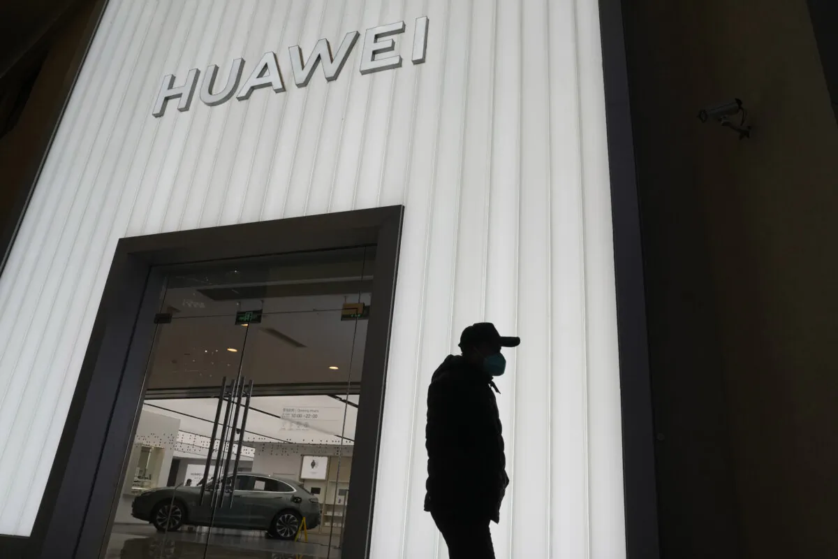 A man is silhouetted outside a Huawei retail store in Beijing on Dec. 30, 2022. (AP-Ng Han Guan/The Canadian Press)