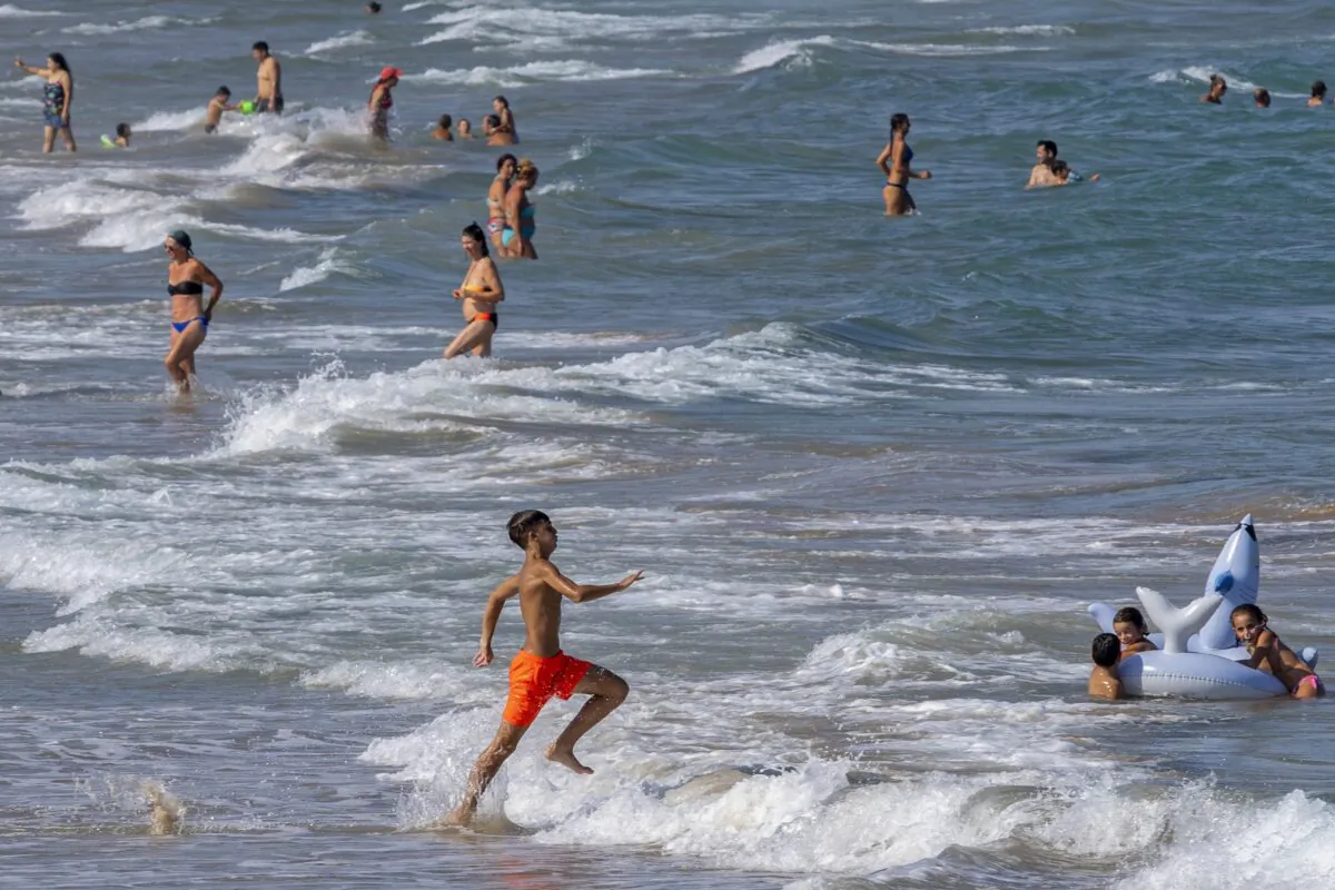 People cool off on Puerto de Sagunto beach in Spain, Tuesday, Aug. 16, 2022. Summer is often a time of having fun, going on vacation and being carefree. But with inflation, layoffs and a looming recession, you may be questioning the financial impact of your summer plans or they suddenly have become out of reach. (Alberto Saiz/AP)