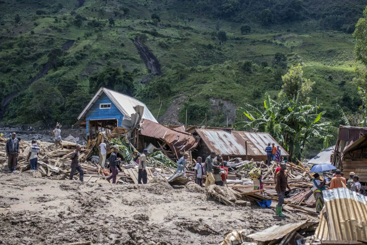 People walk next to houses destroyed by the floods in the village of Nyamukubi, South Kivu province in Congo on May 6, 2023. (Moses Sawasawa/AP Photo)