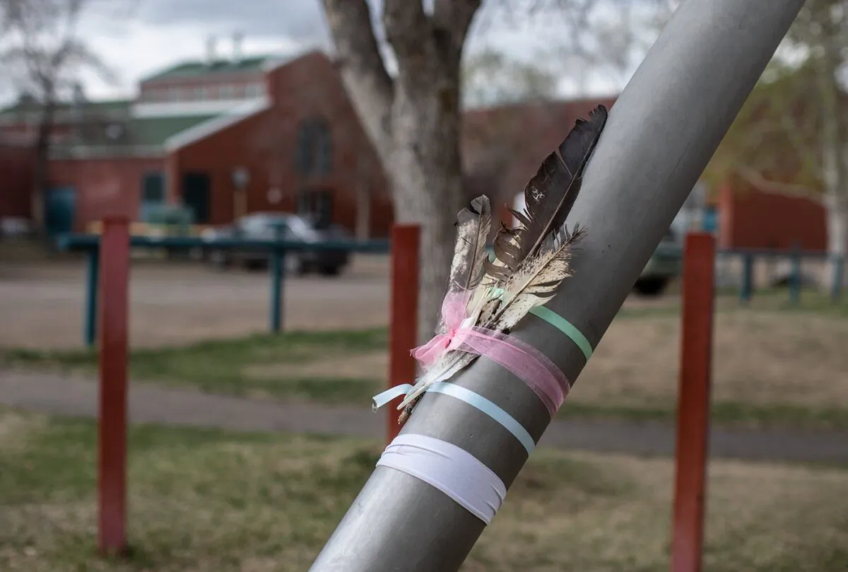 Feathers are placed on a pole for a woman and her 11-year-old child, who were stabbed and killed outside Crawford Plains School, in Edmonton on May 6, 2023. (The Canadian Press/Jason Franson)
