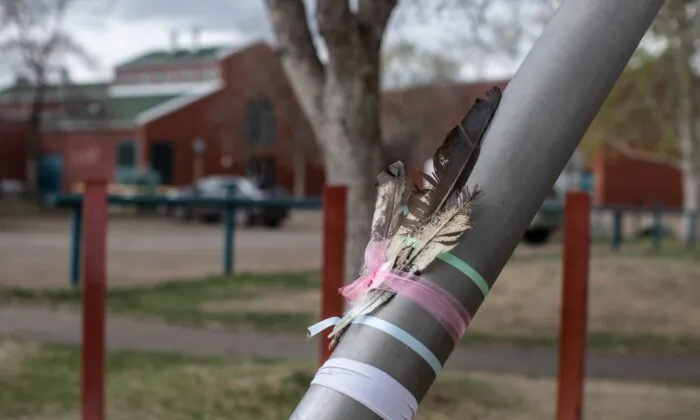 Feathers are placed on a pole for a woman and her 11-year-old child, who were stabbed and killed outside Crawford Plains School, in Edmonton on May 6, 2023. (The Canadian Press/Jason Franson)
