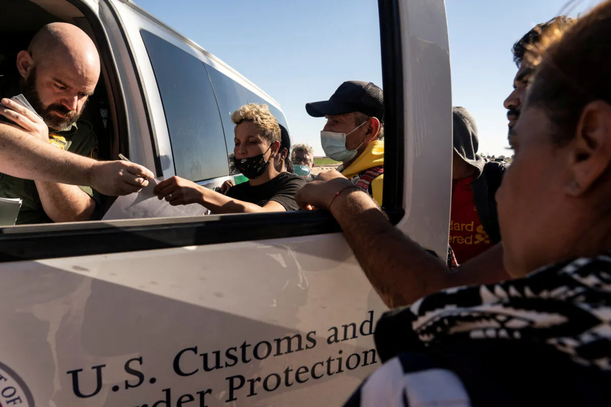 Migrants seeking asylum in the United States from Colombia and Cuba are processed by the U.S. border patrol after crossing the border from Mexico at Yuma, Ariz., on Feb. 18, 2022. (Go Nakamura/Reuters)