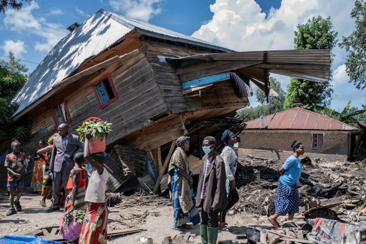 People walk next to a house destroyed by the floods in the village of Nyamukubi, South Kivu province, in Congo, on May 6, 2023. (Moses Sawasawa/AP Photo)