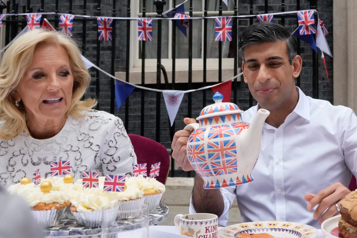 Prime Minister Rishi Sunak holds an oversized tea pot as he goes to pour a cup as he sits next to U.S. First Lady Jill Biden during a Coronation Big Lunch in Downing Street, London, on May 7, 2023. (Frank Augstein/PA Media)