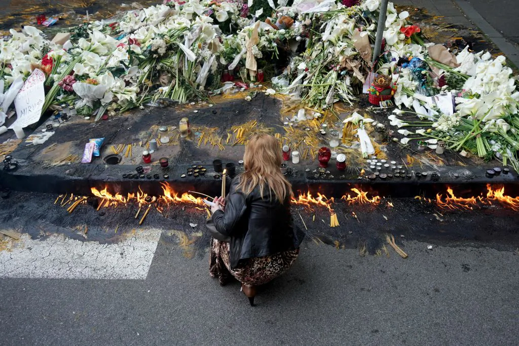 A woman lights candles outside the Vladislav Ribnikar elementary school in the Serbian capital, Belgrade, on May 5, 2023, two days after a 13-year-old suspect shot dead eight fellow students and a security guard after allegedly drawing up a kill list. (Oliver Bunic/AFP via Getty Images)