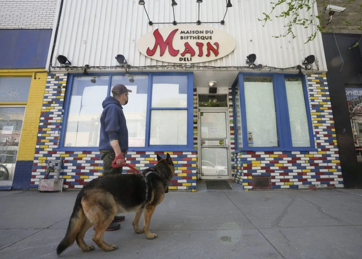 A man reads the closed sign on the Main Deli, on St-Laurent Boulevard, in Montreal, May 9, 2023. (The Canadian Press/Christinne Muschi)