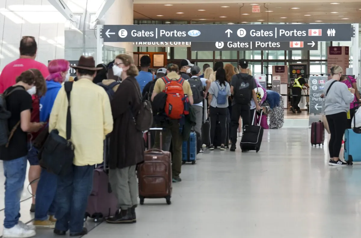 People line up before entering the security zone at Pearson International Airport in Toronto on Aug. 5, 2022. (Nathan Denette/The Canadian Press)