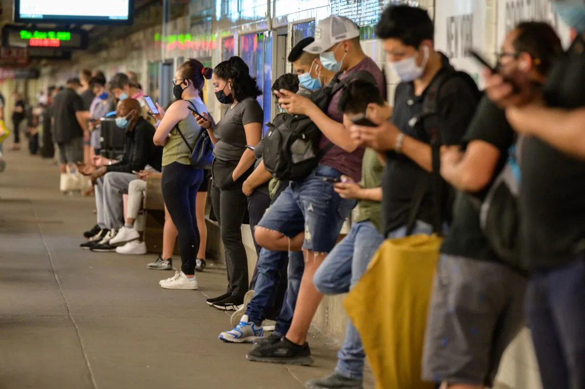 Commuters look at their mobile phones as they wait for a subway train in New York on June 10, 2021. (Ed Jones/AFP via Getty Images)