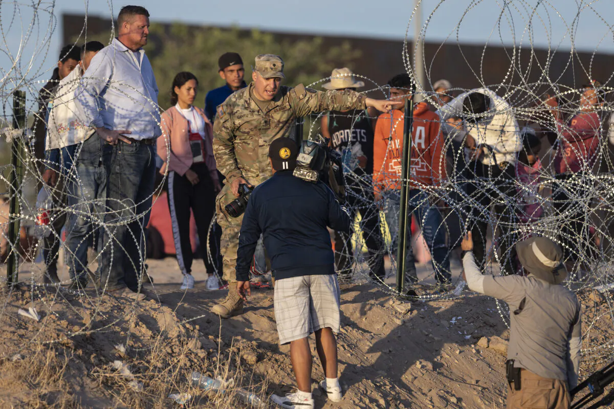 A Texas National Guard soldier bars journalists from approaching migrants who crossed over from Mexico in El Paso, Texas, on May 9, 2023. (John Moore/Getty Images)