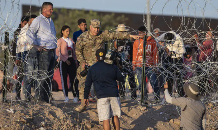 A Texas National Guard soldier bars journalists from approaching migrants who crossed over from Mexico in El Paso, Texas, on May 9, 2023. (John Moore/Getty Images)