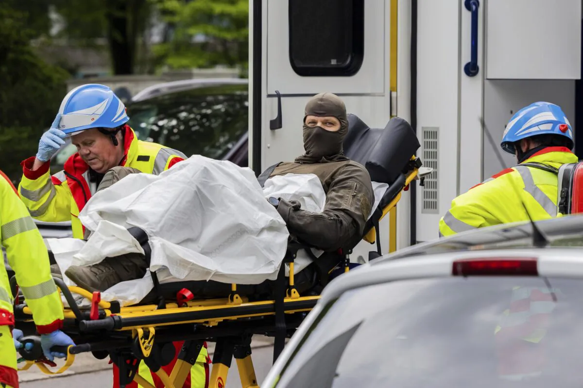 An injured police officer is taken to an ambulance in front of a high-rise building in Ratingen, Germany, on May 11, 2023. (Rolf Vennenbernd/dpa via AP)