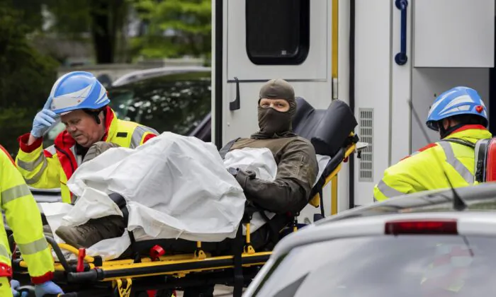 An injured police officer is taken to an ambulance in front of a high-rise building in Ratingen, Germany, on May 11, 2023. (Rolf Vennenbernd/dpa via AP)