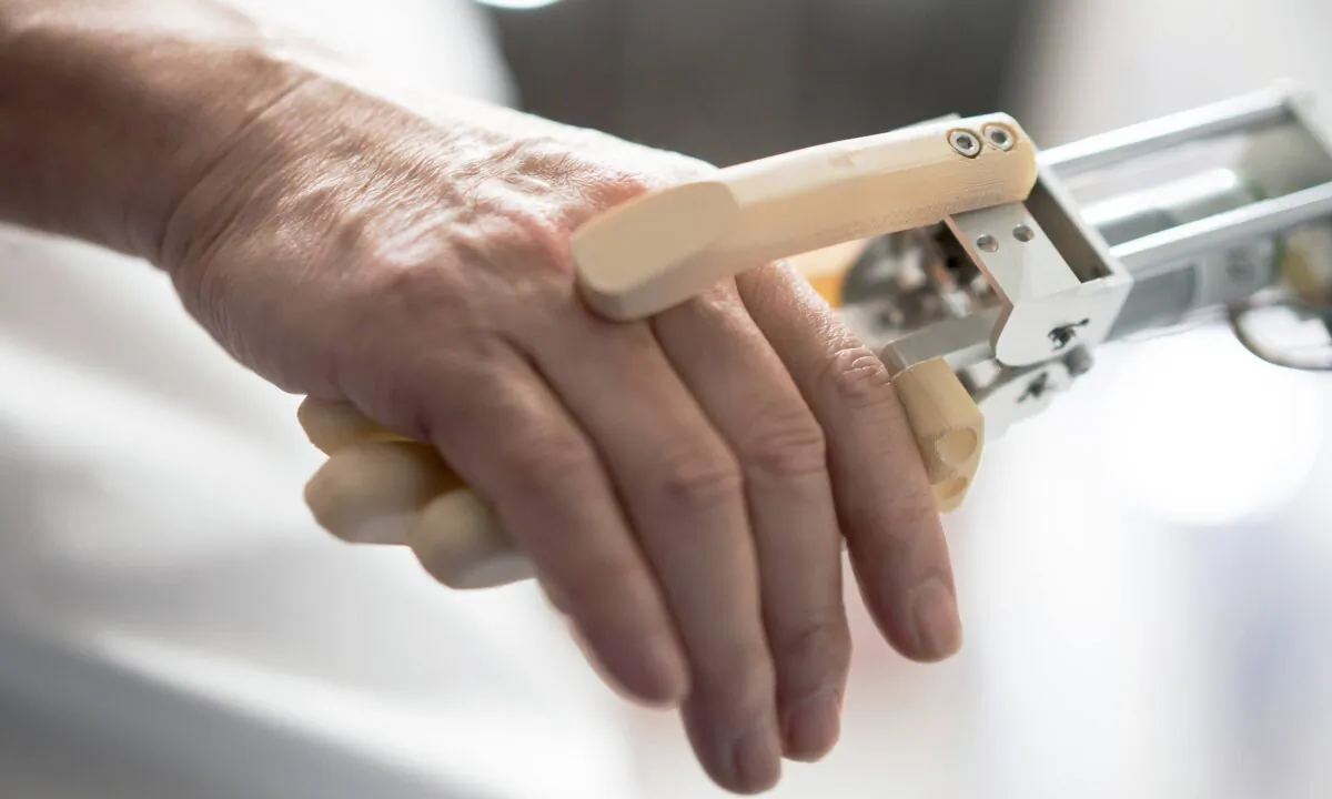 An attendee shakes hands with a robotic arm during the Japan Robot Week 2022 event in Tokyo on Oct. 19, 2022. (Tomohiro Ohsumi/Getty Images)
