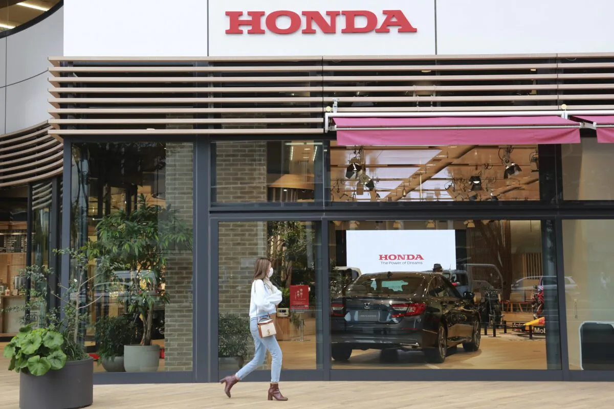 A woman walks past the logo of Honda Motor Co. in Tokyo on Oct. 19, 2021. (Koji Sasahara/AP Photo)