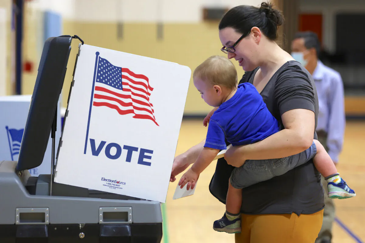 A voter casts her ballot with her child at a polling station at Rose Hill Elementary School during the midterm primary election in Alexandria, Va., on June 21, 2022. (Alex Wong/Getty Images)