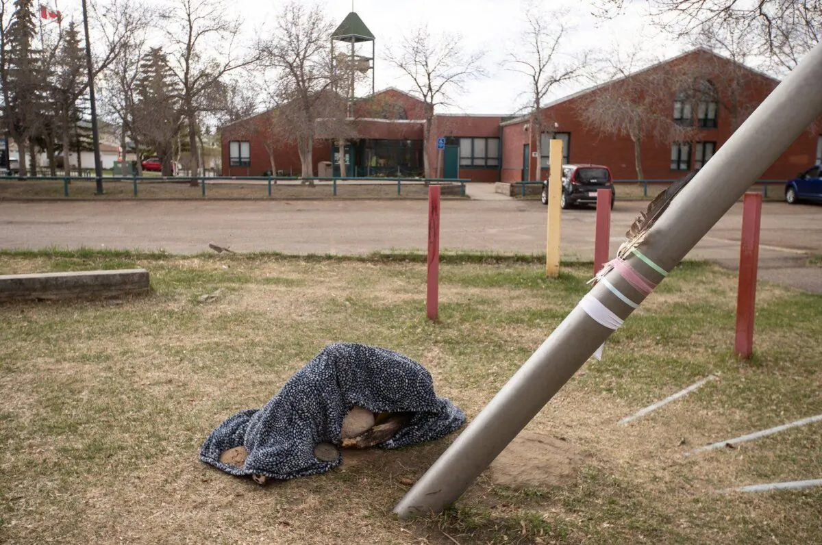 Feathers and a blanket covering flowers are placed for a mother and 11-year-old child that were killed at Crawford Plain School, in Edmonton on May 6, 2023. (The Canadian Press/Jason Franson)