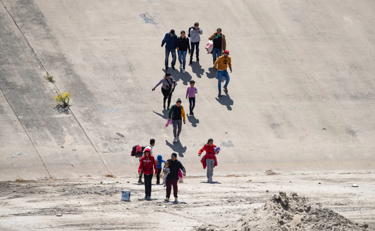 Migrants cross the Tijuana River bed towards the San Diego port of entry to the United States, on May 11, 2023. (John Fredricks/The Epoch Times)