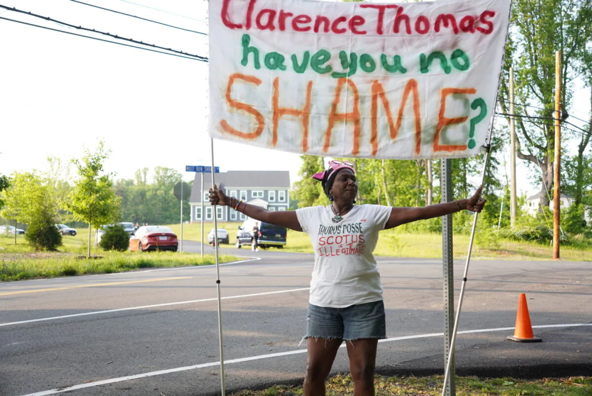 Protester Nadine Seiler holds up a banner during an abortion protest near the home of Justice Clarence Thomas on May 11. (Joseph Lord/The Epoch Times)