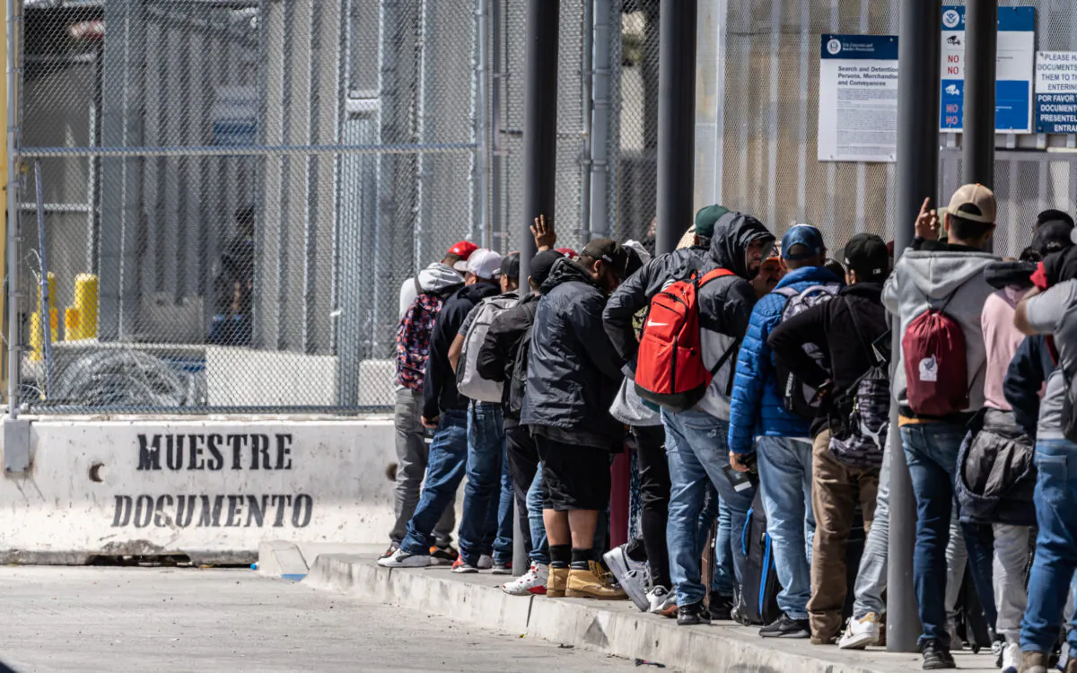 Migrants wait in line to enter the United States from Tijuana, Mexico, on May 11, 2023. (John Fredricks/The Epoch Times)