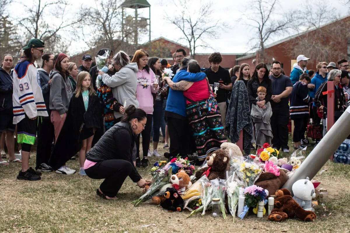 Family and friends console each other during a vigil for Carol Ann Robillard and her 11-year-old daughter Sara Miller who were killed outside a school in Edmonton on May 6, 2023. (The Canadian Press/Jason Franson)